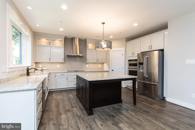 kitchen with dark hardwood / wood-style floors, stainless steel appliances, a center island, pendant lighting, and wall chimney range hood