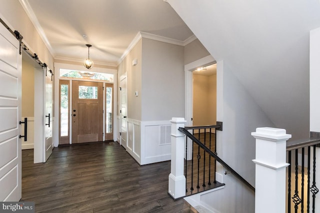 foyer entrance with a barn door, dark hardwood / wood-style floors, and crown molding