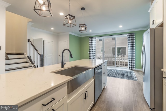 kitchen with hanging light fixtures, ornamental molding, white cabinets, light hardwood / wood-style flooring, and stainless steel appliances