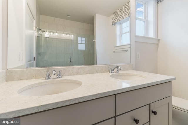 bathroom featuring toilet, dual vanity, and a shower with shower door