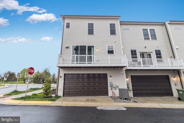 view of front of house featuring a balcony, central AC unit, and a garage