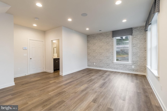 empty room with brick wall, a barn door, and hardwood / wood-style flooring