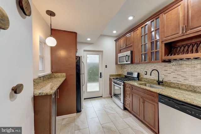 kitchen featuring sink, light tile floors, hanging light fixtures, appliances with stainless steel finishes, and light stone countertops