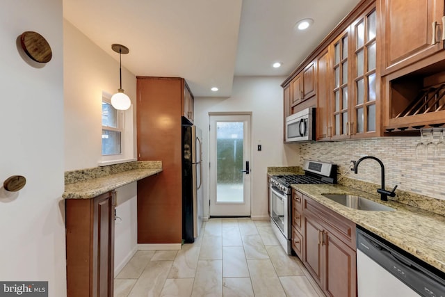 kitchen featuring sink, hanging light fixtures, backsplash, stainless steel appliances, and light stone countertops