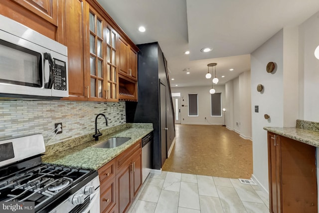 kitchen featuring hanging light fixtures, light stone counters, stainless steel appliances, light tile floors, and sink