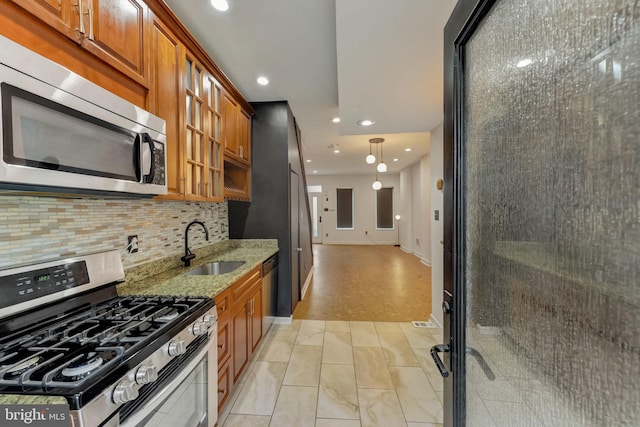 kitchen featuring light hardwood / wood-style floors, appliances with stainless steel finishes, hanging light fixtures, light stone counters, and sink