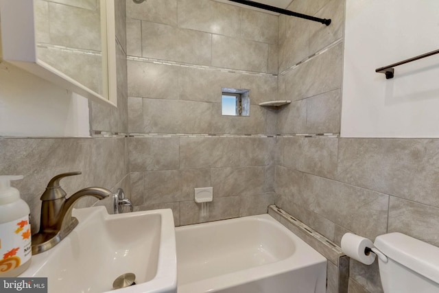 full bathroom featuring tile walls, sink, toilet, and tiled shower / bath combo