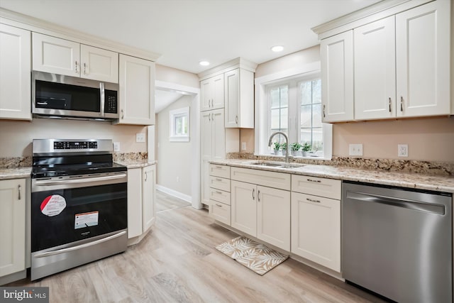 kitchen featuring light stone counters, appliances with stainless steel finishes, sink, and light hardwood / wood-style floors