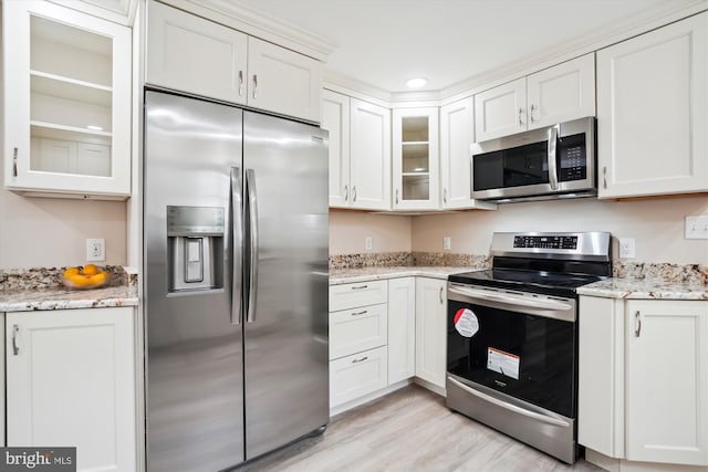 kitchen with white cabinets, appliances with stainless steel finishes, light stone countertops, and light hardwood / wood-style floors