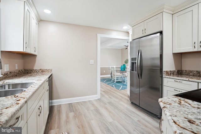 kitchen featuring stainless steel appliances, white cabinetry, light stone countertops, light wood-type flooring, and sink