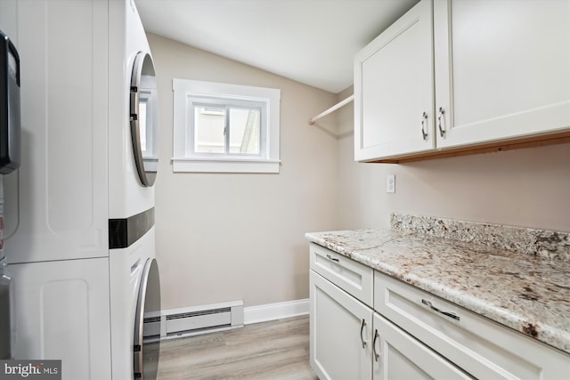 washroom featuring stacked washer / dryer, cabinets, a baseboard radiator, and light hardwood / wood-style flooring