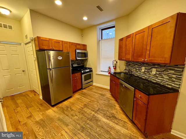 kitchen featuring tasteful backsplash, sink, light hardwood / wood-style flooring, and appliances with stainless steel finishes