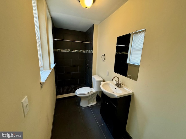 bathroom featuring tiled shower, tile patterned floors, vanity, and toilet