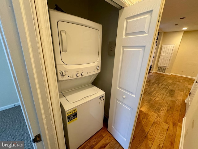 laundry area featuring hardwood / wood-style floors and stacked washer and dryer