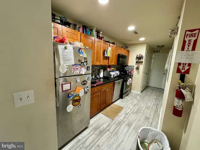 kitchen featuring tasteful backsplash, sink, stainless steel appliances, and light wood-type flooring