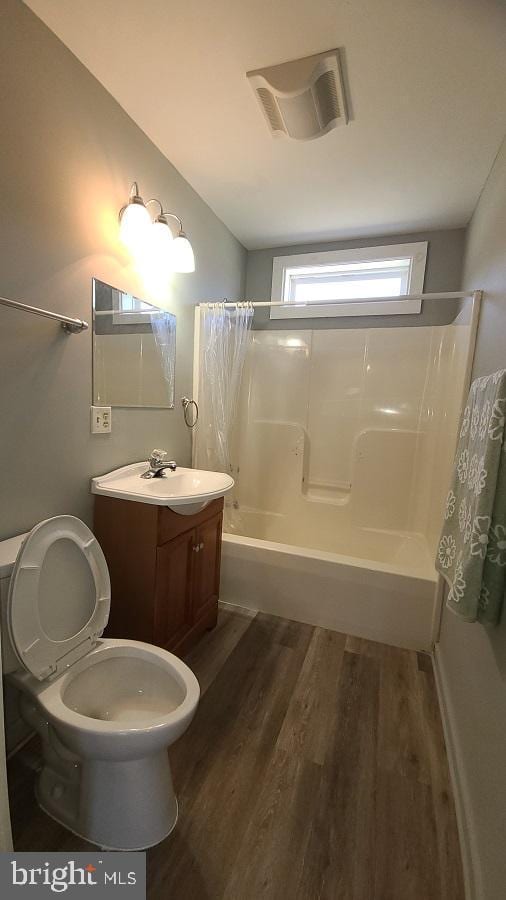 full bathroom with toilet, shower / bath combo with shower curtain, vanity with extensive cabinet space, and hardwood / wood-style flooring