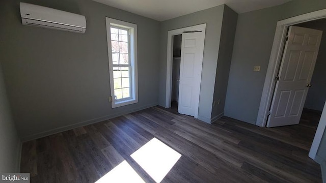 unfurnished bedroom with a wall mounted air conditioner, a closet, multiple windows, and dark hardwood / wood-style flooring