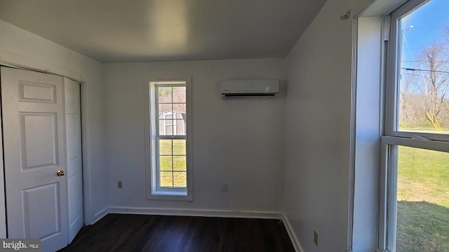 unfurnished bedroom featuring dark wood-type flooring, a wall unit AC, and a closet