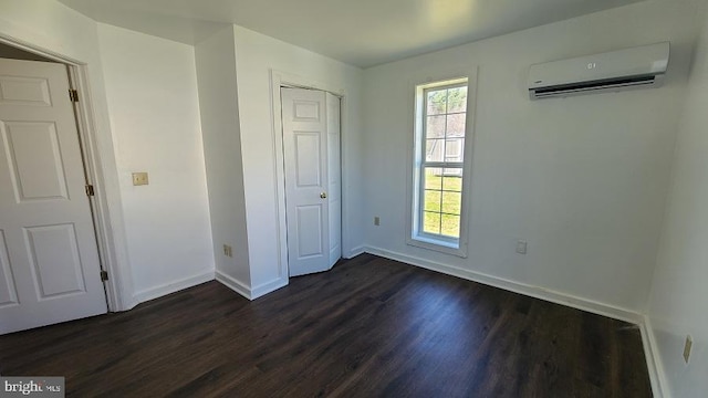 unfurnished bedroom with a closet, dark wood-type flooring, and a wall mounted AC