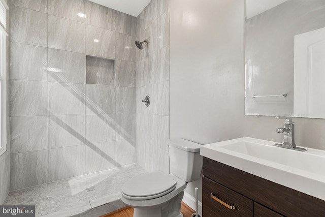 bathroom with vanity, a tile shower, hardwood / wood-style floors, and toilet