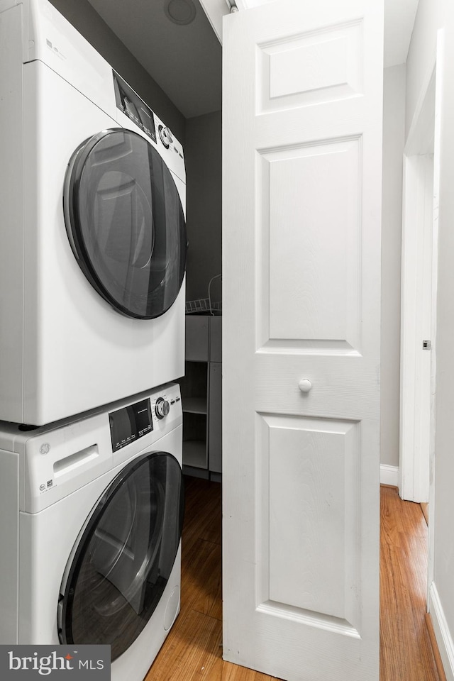 laundry room with light hardwood / wood-style floors and stacked washer / dryer