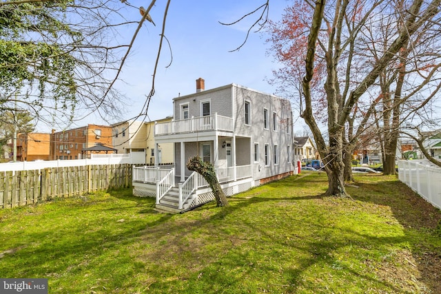 rear view of property featuring a lawn and a balcony