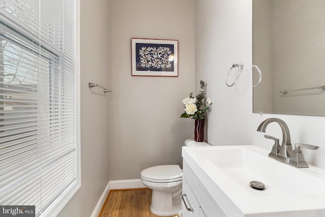 bathroom with large vanity, toilet, and hardwood / wood-style flooring