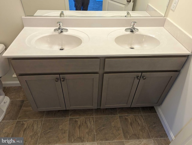 bathroom with toilet and double sink vanity