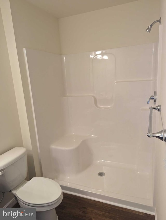 bathroom with hardwood / wood-style floors, walk in shower, and toilet