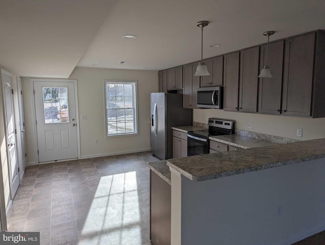 kitchen featuring appliances with stainless steel finishes, decorative light fixtures, light tile patterned flooring, and kitchen peninsula