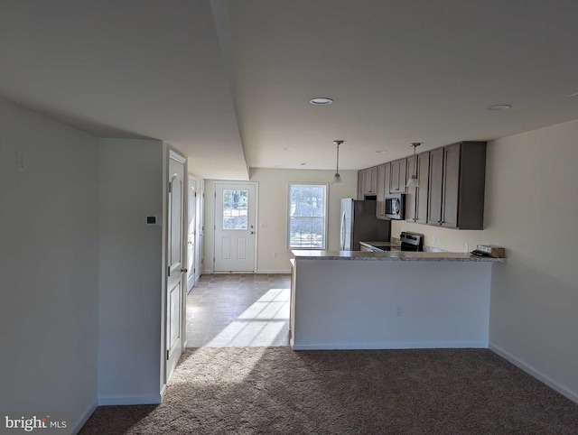 kitchen with appliances with stainless steel finishes, light stone counters, kitchen peninsula, light carpet, and hanging light fixtures