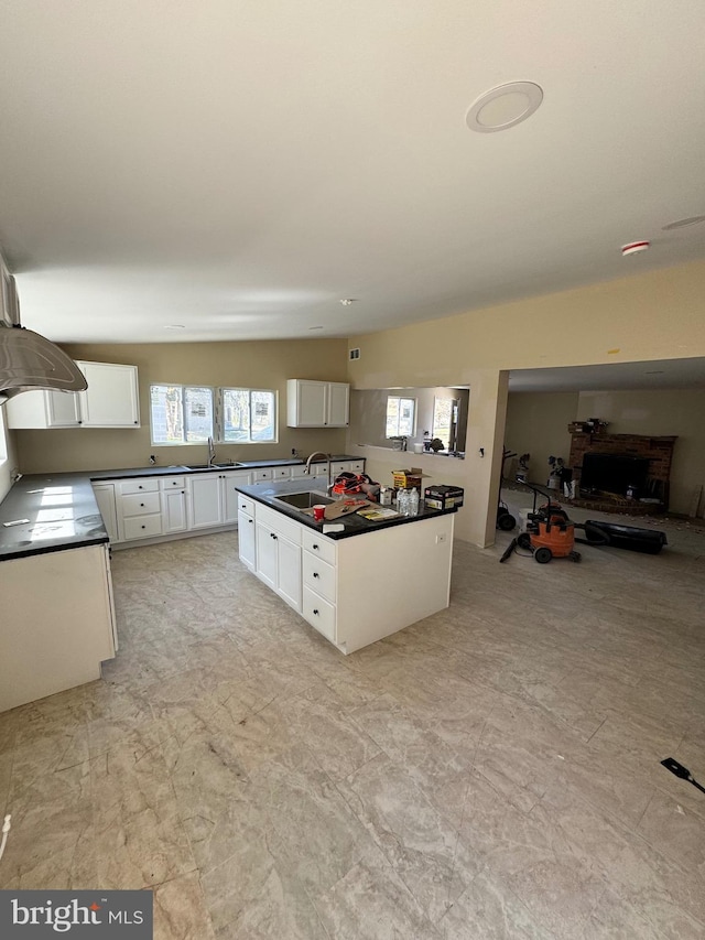 kitchen with white cabinets, a center island with sink, light tile floors, and sink