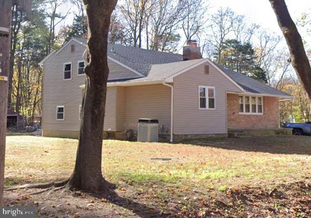 view of side of property with central air condition unit and a yard