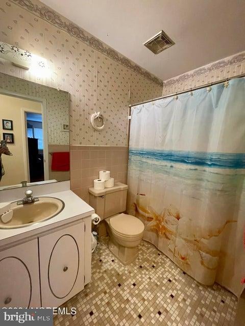 bathroom featuring vanity, tile flooring, toilet, and tile walls