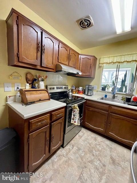 kitchen featuring light tile flooring, dark brown cabinets, stainless steel range with electric cooktop, and sink