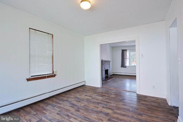 unfurnished living room with a baseboard radiator, dark wood-type flooring, a brick fireplace, and a textured ceiling