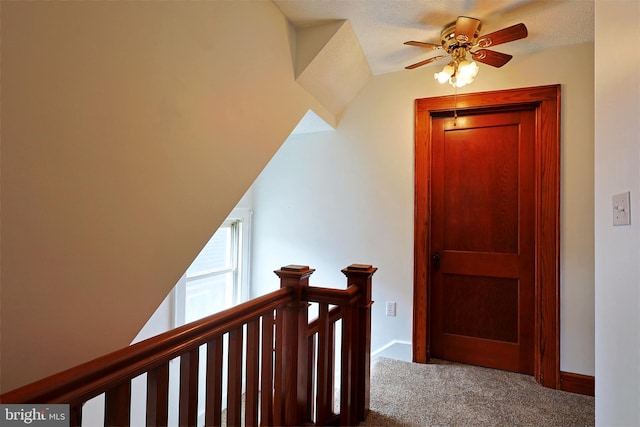 hall with carpet, vaulted ceiling, and a textured ceiling