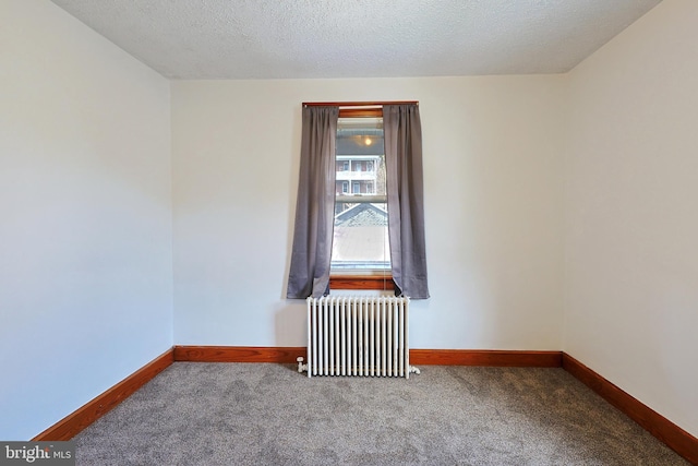 empty room featuring radiator, dark carpet, and a textured ceiling