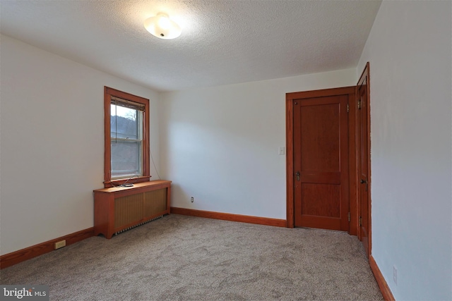 carpeted empty room featuring a textured ceiling