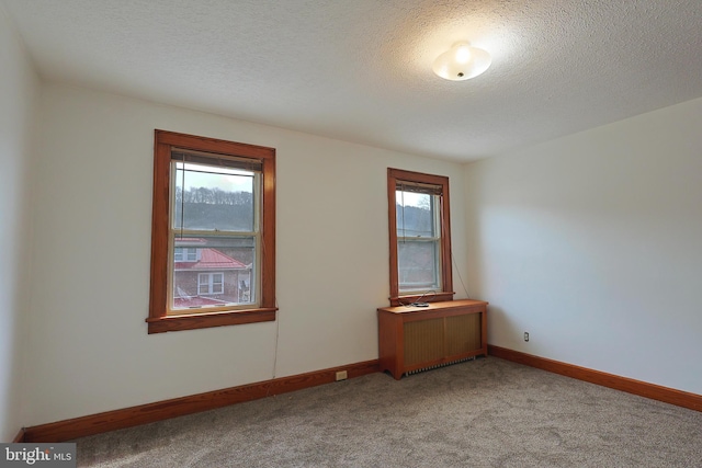 carpeted spare room with a textured ceiling and radiator heating unit