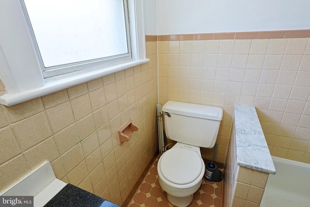 bathroom featuring tile walls, tile flooring, and toilet