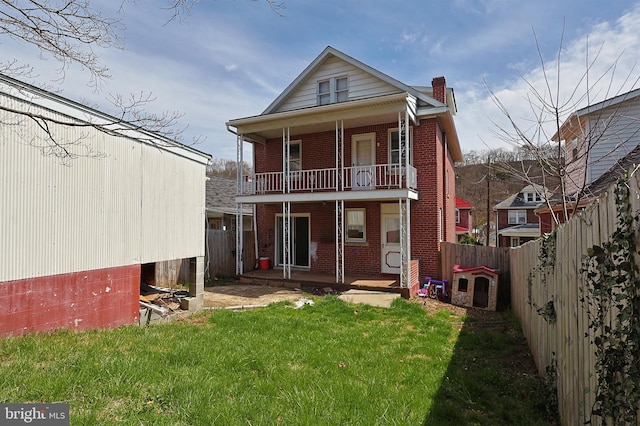 rear view of property featuring a balcony and a lawn