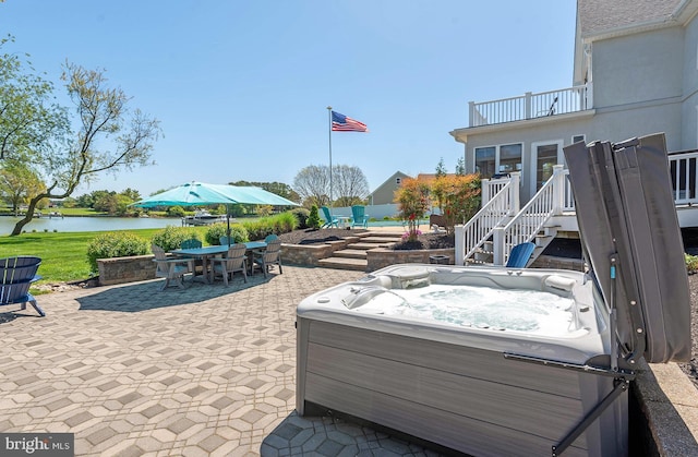 view of patio / terrace featuring a water view, a balcony, and a hot tub