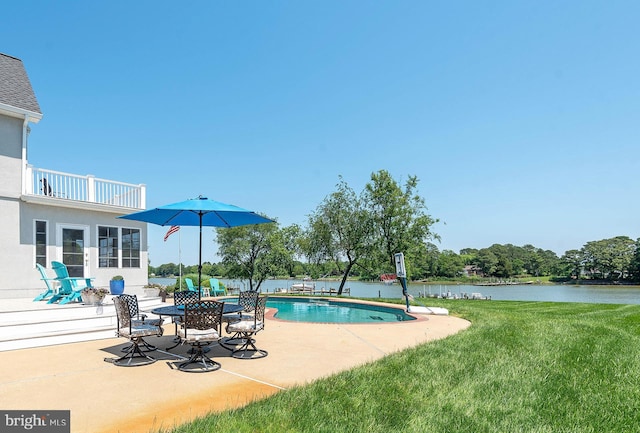 view of pool with a patio, a water view, and a lawn