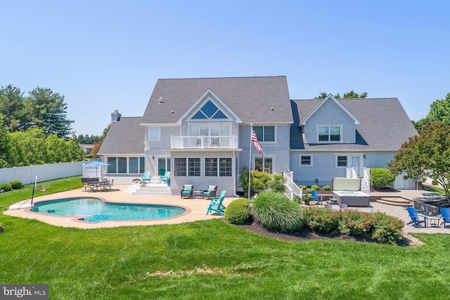 back of house featuring an outdoor hangout area, a balcony, a patio area, a yard, and a fenced in pool