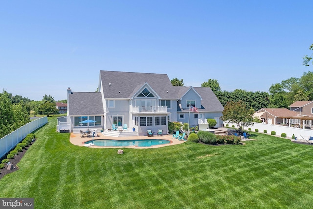 rear view of house featuring a patio area, a balcony, a fenced in pool, and a yard