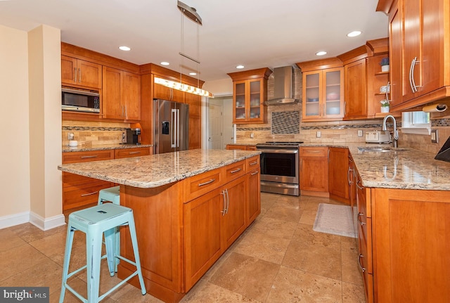 kitchen featuring a center island, wall chimney range hood, sink, a kitchen bar, and stainless steel appliances