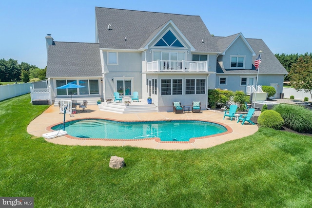 back of property featuring a lawn, a balcony, and a patio