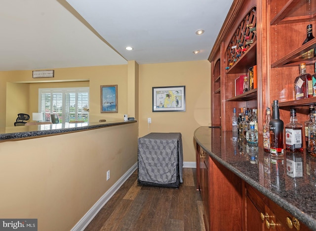 bar featuring dark hardwood / wood-style flooring and dark stone counters