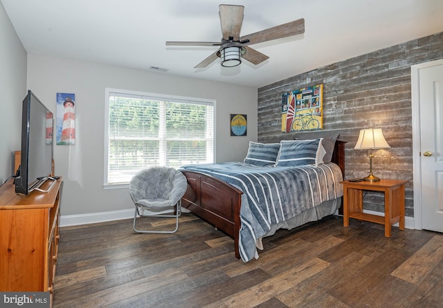 bedroom with dark wood-type flooring, ceiling fan, and wooden walls